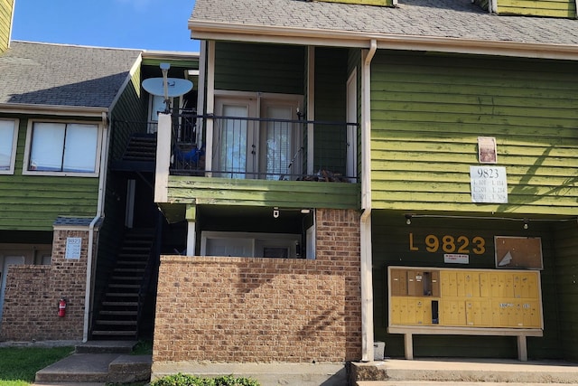 property entrance with roof with shingles and a balcony