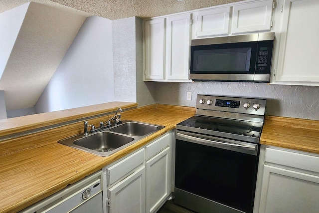 kitchen with a sink, appliances with stainless steel finishes, a textured ceiling, and wood counters