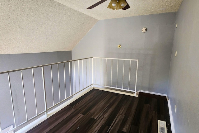 additional living space featuring visible vents, wood finished floors, a textured ceiling, a ceiling fan, and vaulted ceiling