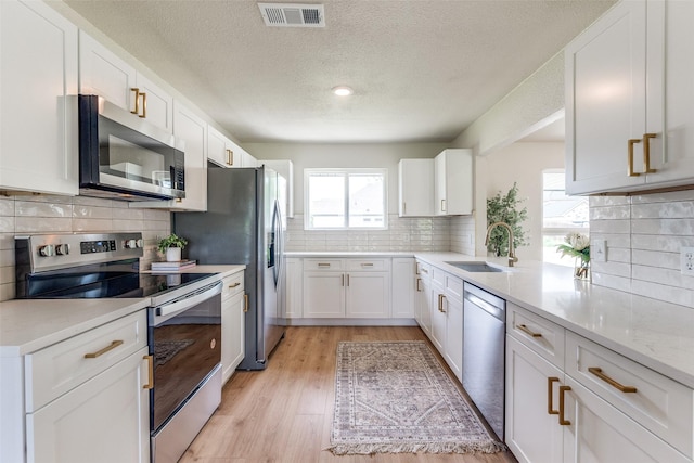 kitchen featuring tasteful backsplash, a sink, a textured ceiling, appliances with stainless steel finishes, and visible vents