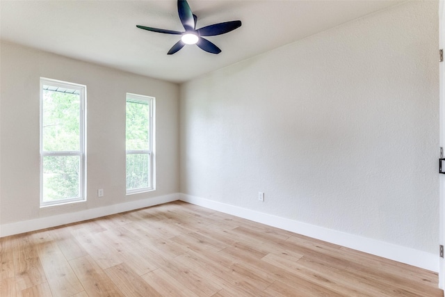 spare room featuring light wood finished floors, baseboards, and ceiling fan