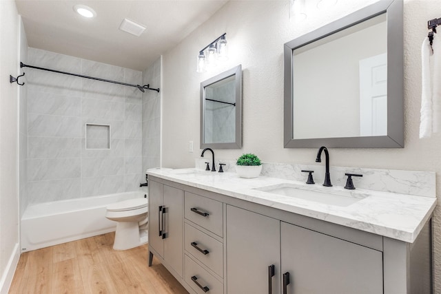 full bath with wood finished floors, a sink, double vanity, and toilet