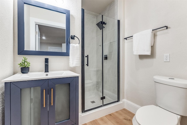 full bathroom featuring a stall shower, toilet, baseboards, wood finished floors, and vanity