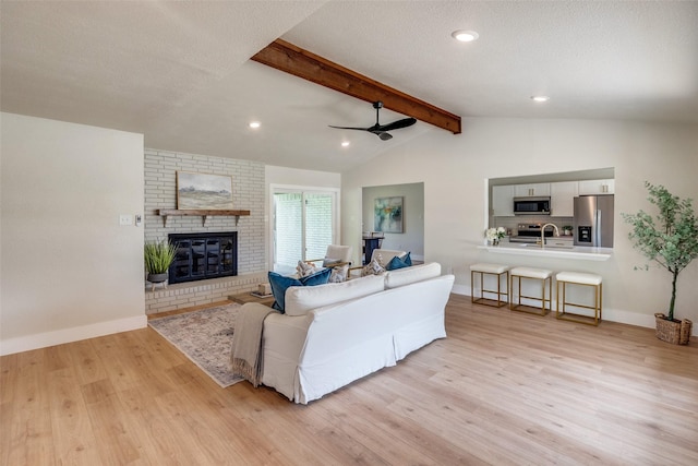 living room with baseboards, a ceiling fan, vaulted ceiling with beams, and light wood finished floors