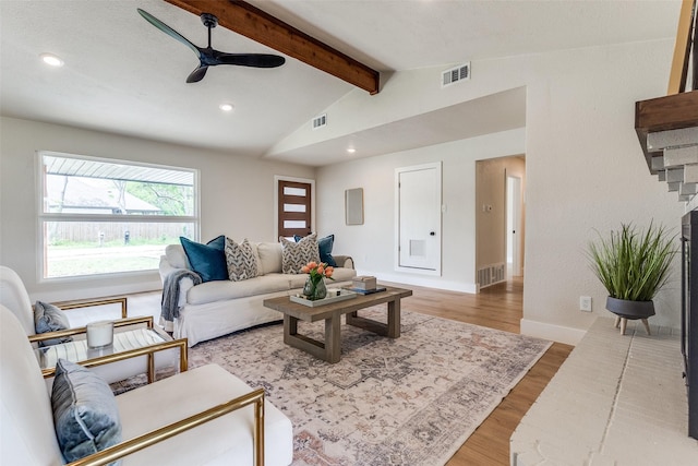 living area with wood finished floors, visible vents, and vaulted ceiling with beams