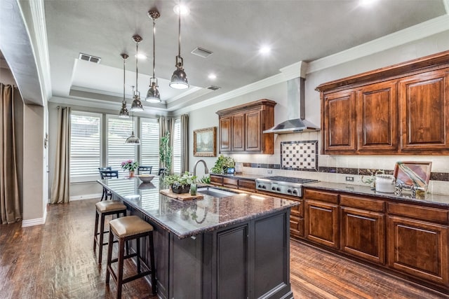 kitchen featuring wall chimney exhaust hood, a sink, dark wood finished floors, visible vents, and stainless steel gas stovetop