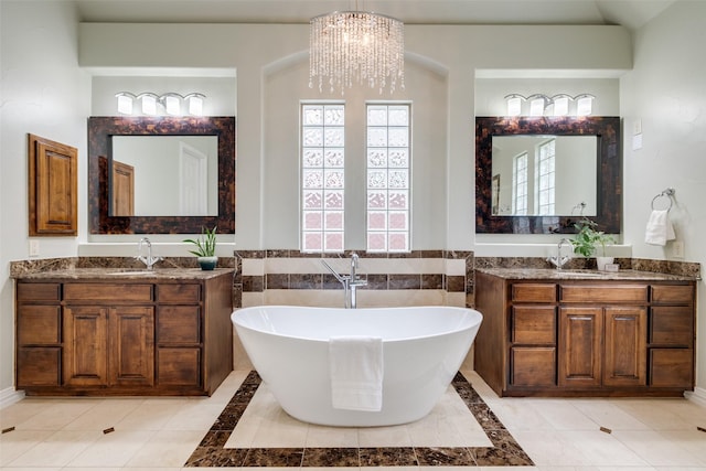 full bathroom with tile patterned floors, a freestanding tub, a sink, and a chandelier