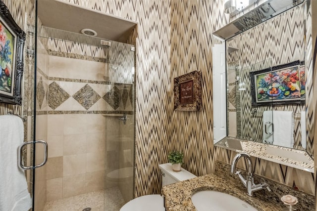 full bath featuring wallpapered walls, vanity, a shower stall, and toilet