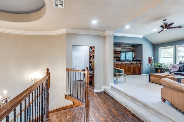 corridor with wood finished floors, visible vents, an upstairs landing, crown molding, and baseboards