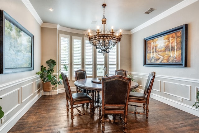 dining room featuring dark wood finished floors, visible vents, ornamental molding, a decorative wall, and a chandelier