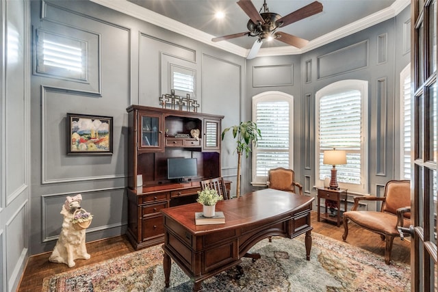 office space featuring wood finished floors, a decorative wall, ceiling fan, and ornamental molding