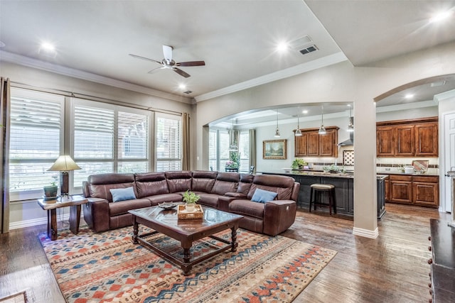 living room with ceiling fan, arched walkways, ornamental molding, and wood finished floors