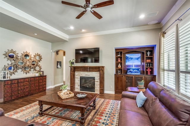 living area featuring wood finished floors, arched walkways, ceiling fan, and crown molding