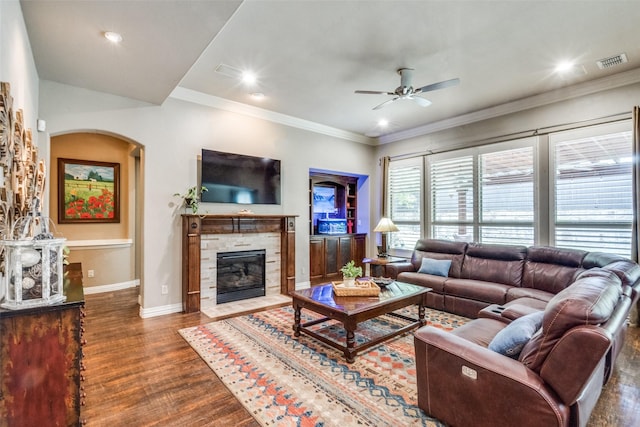 living room with wood finished floors, visible vents, arched walkways, a fireplace, and ceiling fan