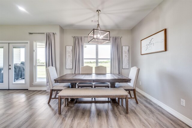 dining area with baseboards, french doors, a chandelier, and light wood-style floors