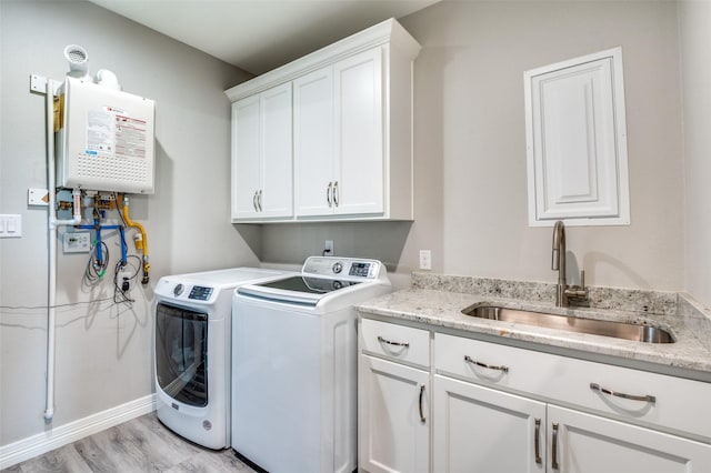 laundry room with light wood finished floors, a sink, water heater, cabinet space, and washer and dryer