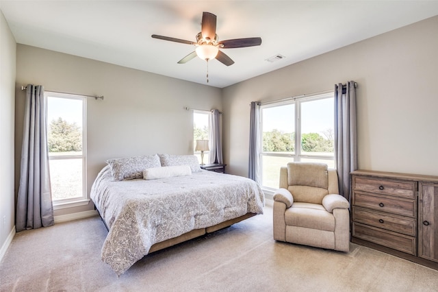 bedroom with visible vents, a ceiling fan, baseboards, and light carpet