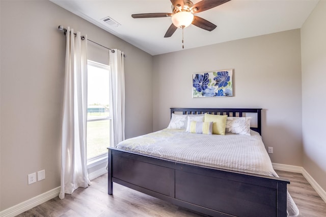bedroom featuring baseboards, multiple windows, and light wood finished floors