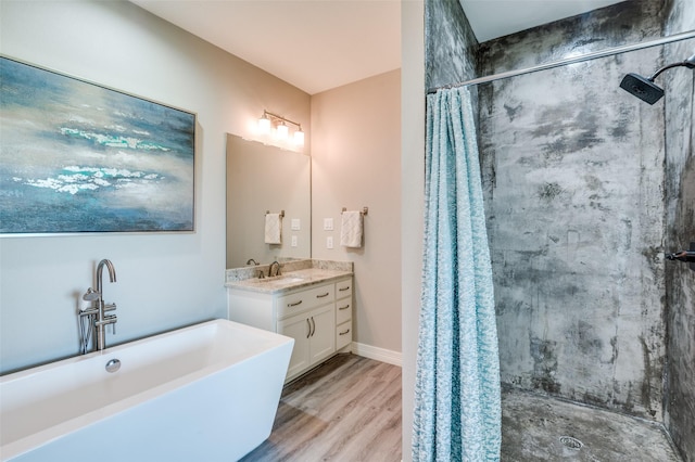 bathroom with wood finished floors, vanity, a stall shower, and a soaking tub