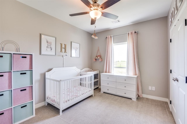 bedroom with baseboards, visible vents, light colored carpet, a closet, and a crib