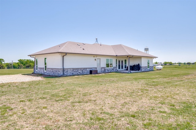 rear view of house with cooling unit, a patio area, and a lawn