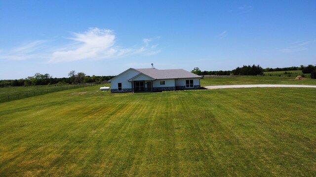 view of front of home featuring a front lawn, stone siding, and a rural view