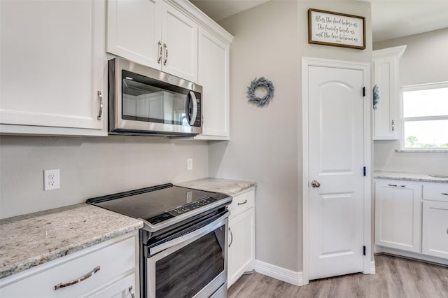 kitchen featuring white cabinets, light stone countertops, stainless steel appliances, and light wood-type flooring