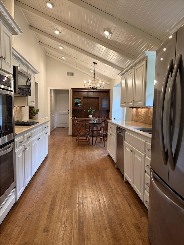 11147 Carissa Dr, Dallas, TX 75218 - kitchen with stainless steel appliances, an inviting chandelier, backsplash, visible vents, and lofted ceiling with beams