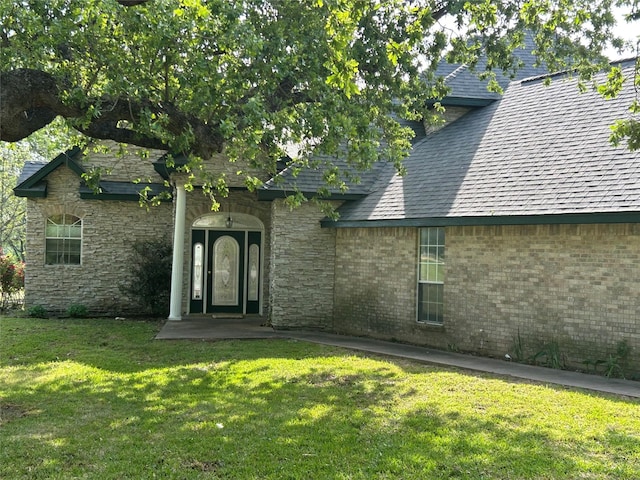 exterior space with stone siding and a lawn