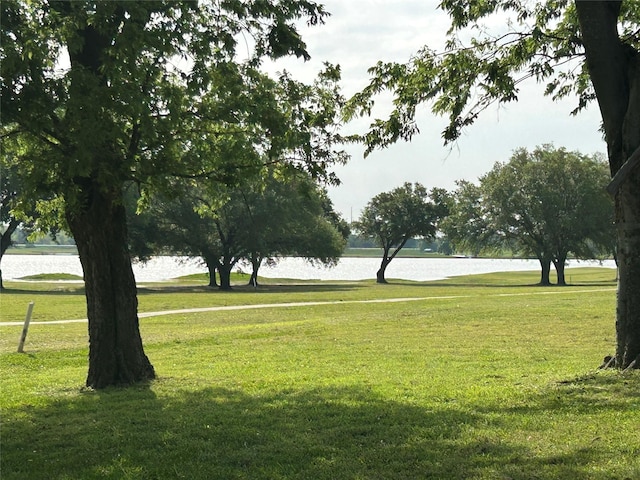 surrounding community with a water view and a yard
