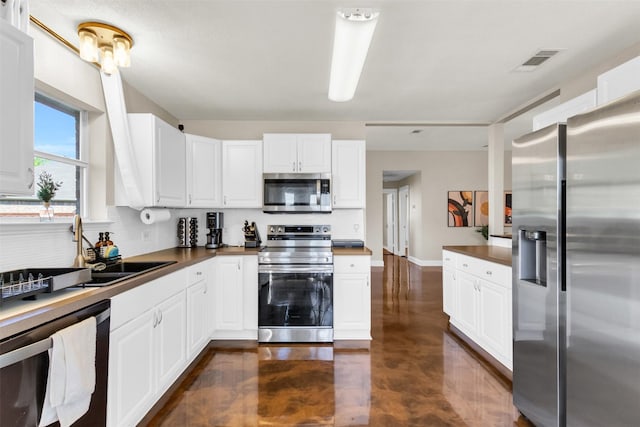 500 Nathan St, Saginaw, TX 76179 - kitchen with stainless steel appliances, white cabinets, a sink, and finished concrete floors