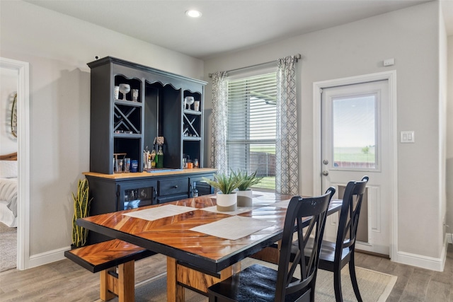 dining area with light wood-style flooring, baseboards, and a bar