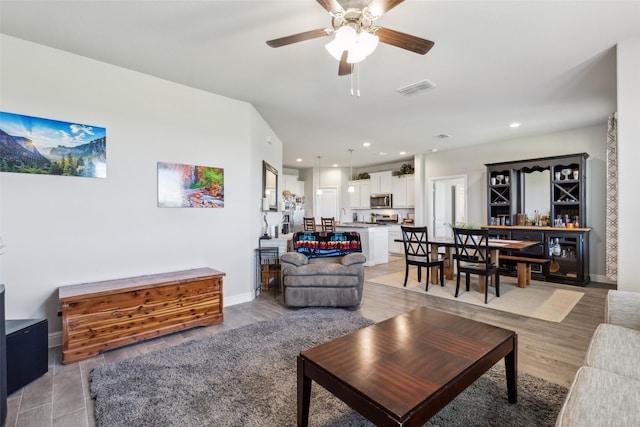 living area with recessed lighting, visible vents, a ceiling fan, and baseboards