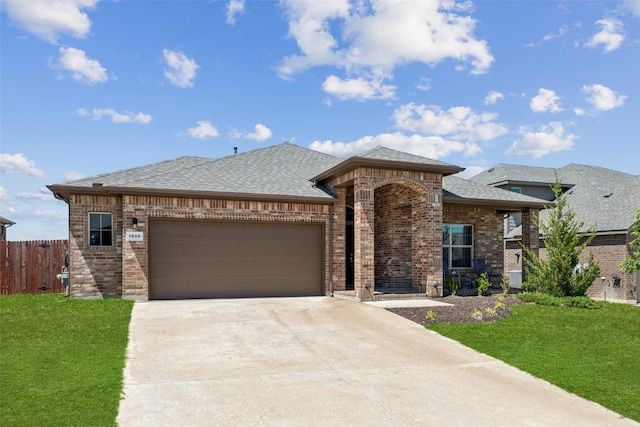 prairie-style home featuring brick siding, concrete driveway, a front yard, and a garage