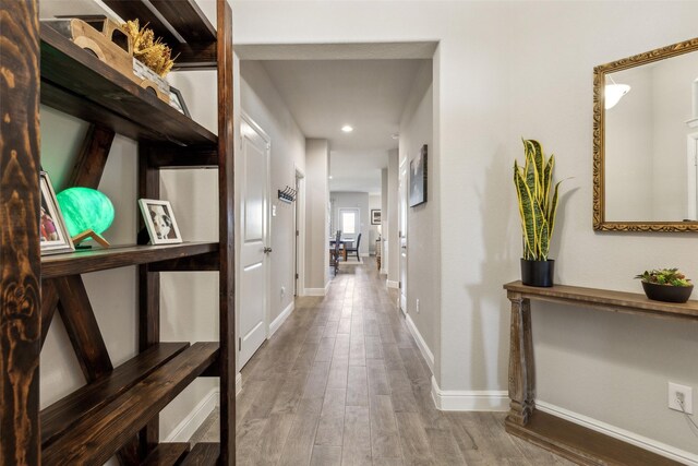 hallway featuring recessed lighting, wood finished floors, and baseboards