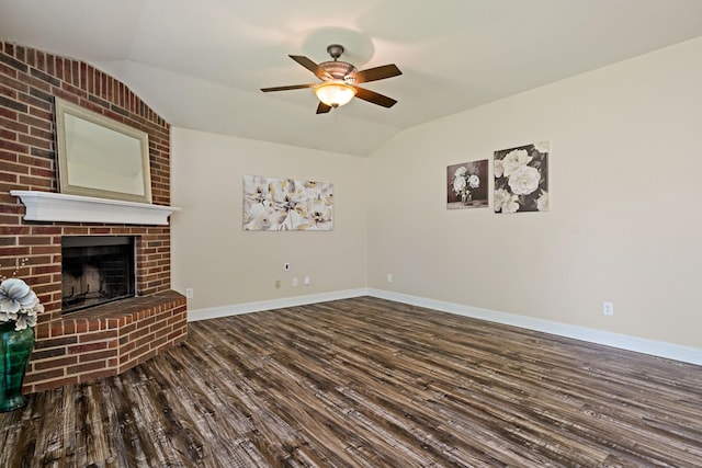 unfurnished living room with lofted ceiling, wood finished floors, a ceiling fan, baseboards, and a brick fireplace