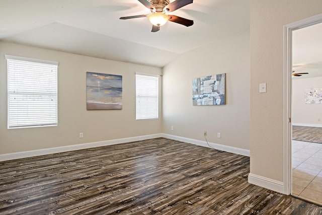 spare room with ceiling fan, lofted ceiling, dark wood-style flooring, and baseboards