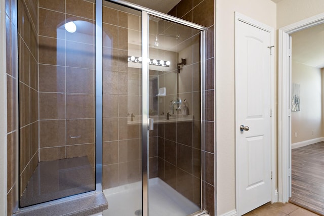bathroom featuring a shower stall, baseboards, and tile patterned floors