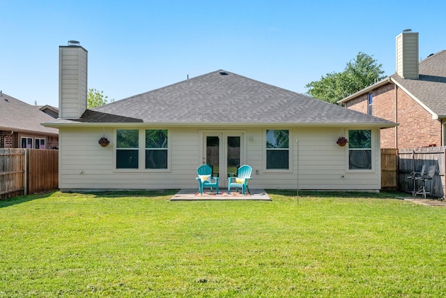 back of property with a fenced backyard, roof with shingles, and a yard