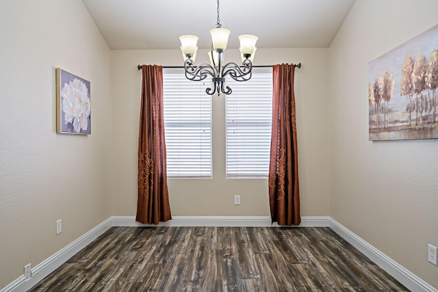 unfurnished dining area with an inviting chandelier, dark wood-style floors, and baseboards