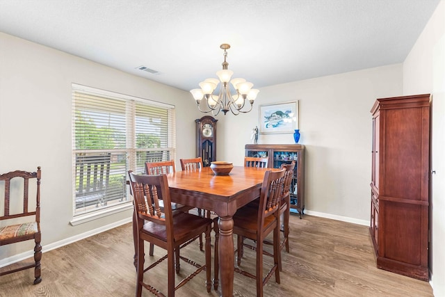 dining room with light wood-type flooring, visible vents, baseboards, and a notable chandelier