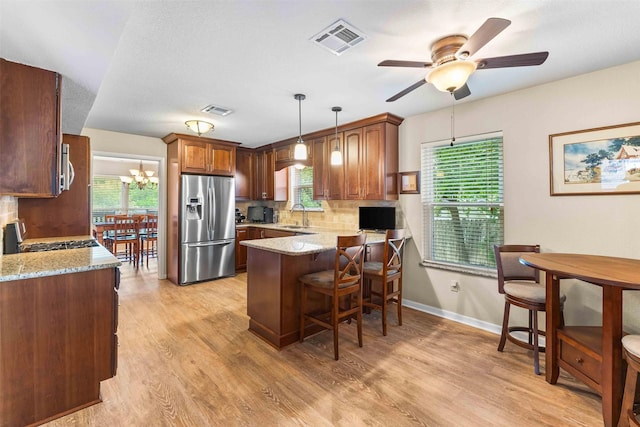 kitchen with light wood finished floors, stainless steel appliances, a peninsula, a sink, and visible vents