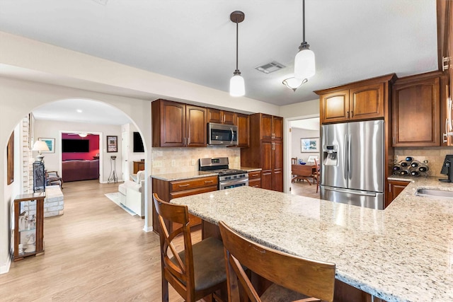 kitchen with visible vents, a sink, arched walkways, decorative backsplash, and appliances with stainless steel finishes
