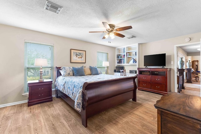 bedroom with a textured ceiling, light wood-type flooring, and visible vents