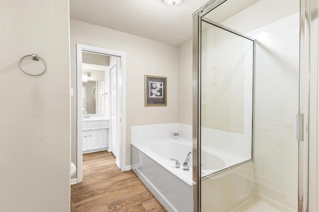 bathroom featuring a bath, vanity, wood finished floors, and a shower stall
