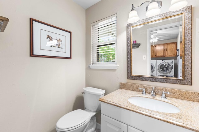 half bathroom with washing machine and dryer, toilet, vanity, and ceiling fan