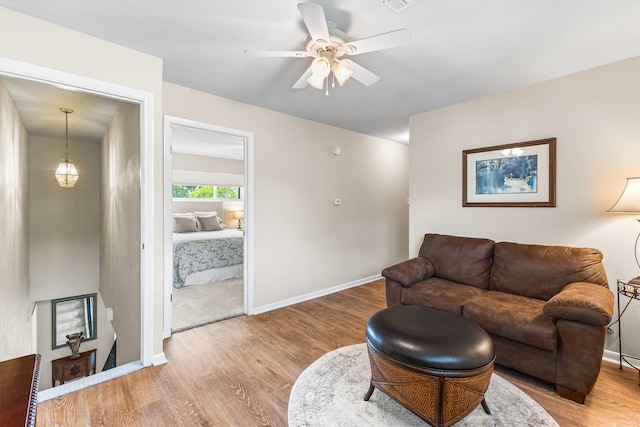 living area featuring baseboards, a ceiling fan, wood finished floors, and visible vents