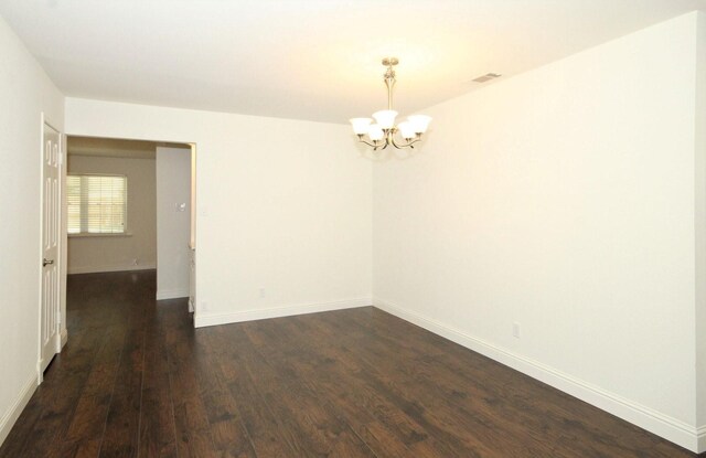 unfurnished room featuring baseboards, dark wood-style flooring, a chandelier, and visible vents