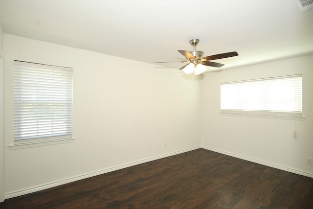 spare room featuring plenty of natural light, visible vents, ceiling fan, and dark wood-style flooring