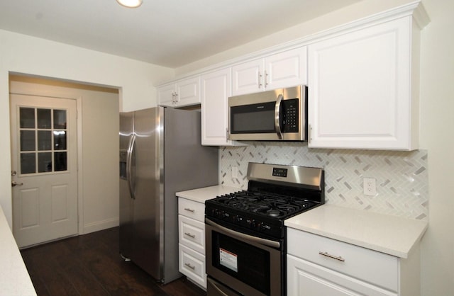 kitchen with stainless steel appliances, light countertops, backsplash, white cabinetry, and dark wood-style floors